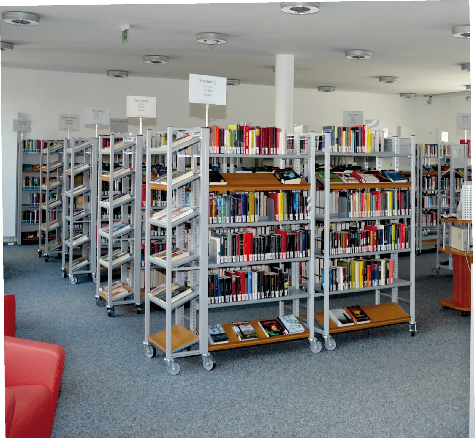 Stirnseitenregale in Verbindung mit Grundregalen beleben die Bibliothek — Stadtbibliothek München — Neuhauser Trafo, München